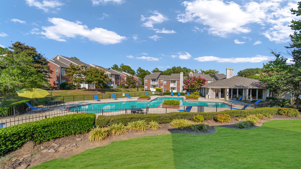 A large grassy area with a pool and a building in the background.