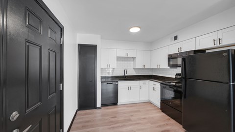A modern kitchen with black cabinets and white appliances. at The District Apartments, Tennessee, 38115