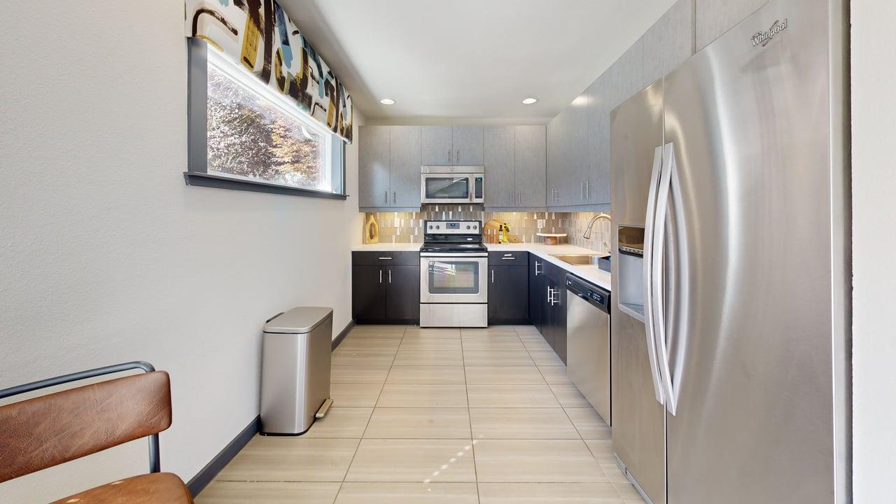 A modern kitchen with stainless steel appliances and a wooden bench.