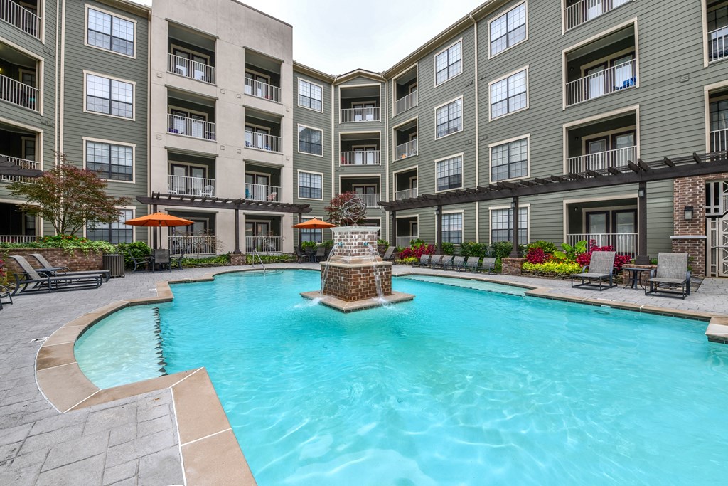 a swimming pool with a fountain in front of an apartment building