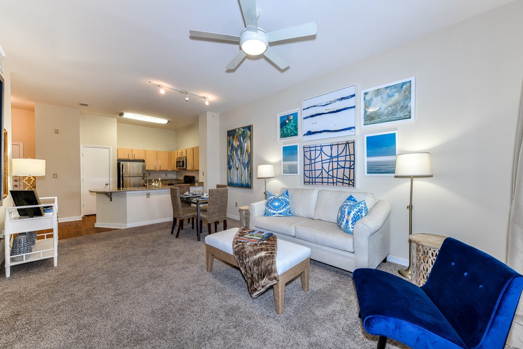 a living room with a couch coffee table and chairs and a kitchen in the background