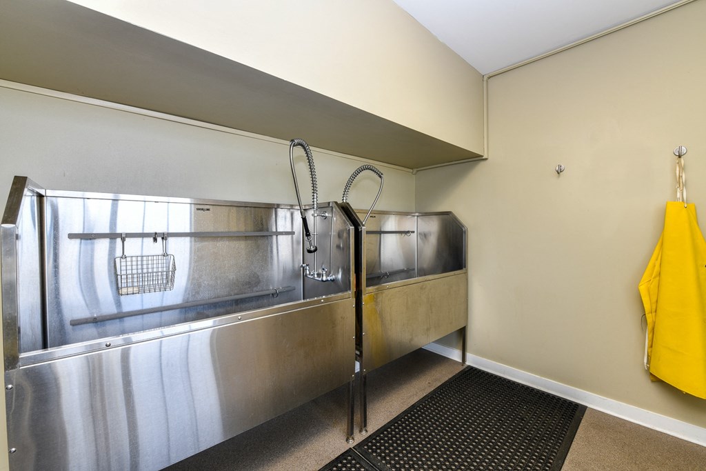 a large stainless steel sink in a kitchen with a yellow tote bag hanging on the wall