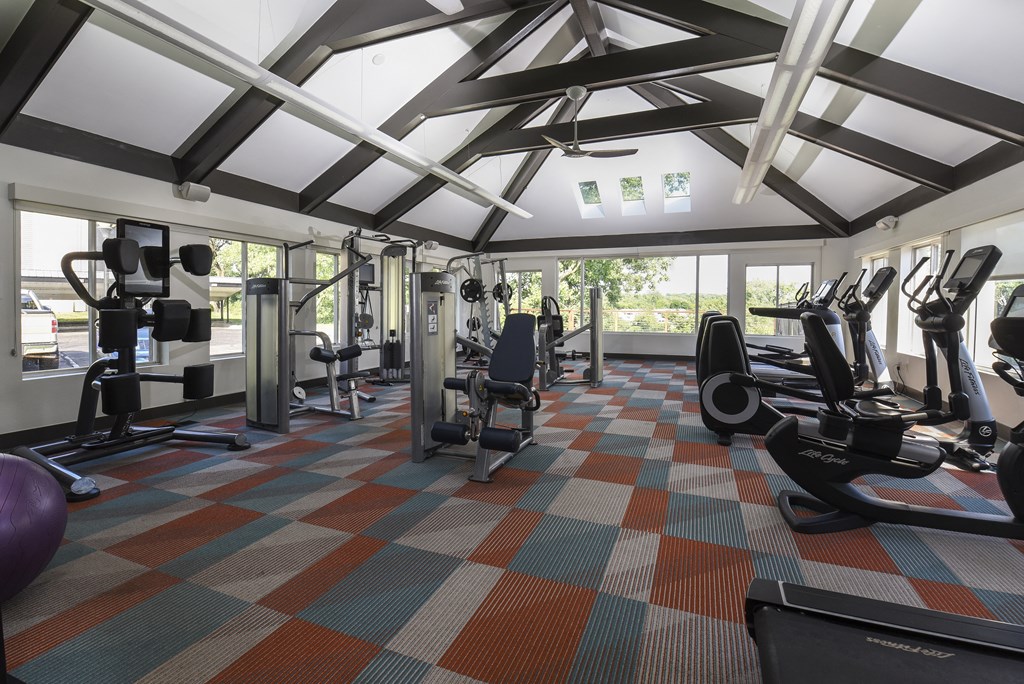 a large fitness room with cardio machines and weights