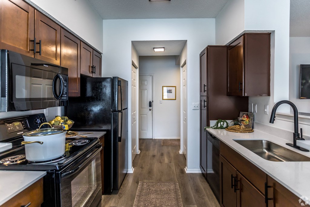 full kitchen with black appliances and wood flooring at theolan apartments at The Grove Germantown Apartments, Germantown, TN ?