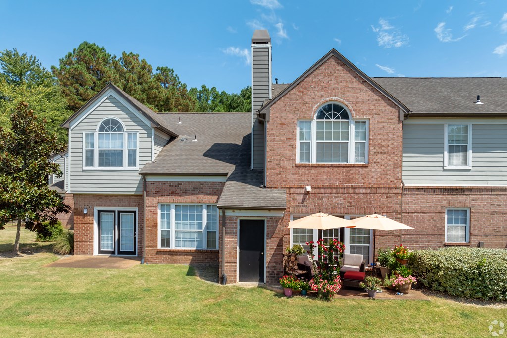 the front of a brick building with an umbrella on the patio at The Grove Germantown Apartments, Germantown, TN 38138 ?