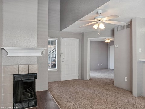 A living room with a fireplace and a ceiling fan.