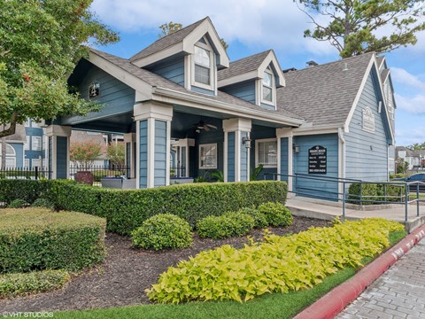 A blue house with a porch and a sign on the front.