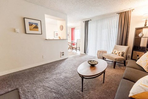 A living room with a grey carpet and a brown coffee table.
