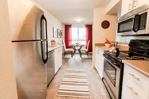 A kitchen with a refrigerator on the left and a microwave on the right.