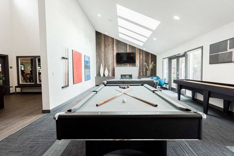 A pool table is in the middle of a room with a TV and a fireplace.