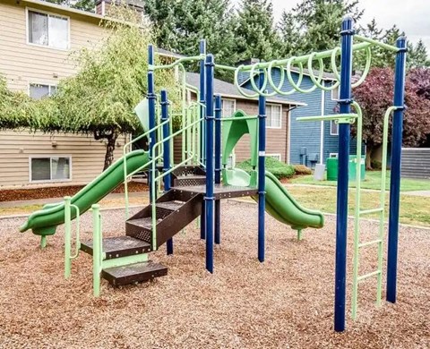 A playground with a green slide and a wooden platform.