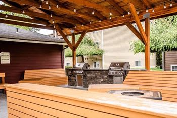 A wooden covered patio with a grill and picnic table at Altitude Apartment , Tacoma