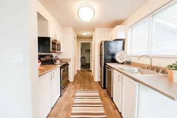 A kitchen with white cabinets and a striped rug on the floor at Altitude Apartment , Washington, 98444