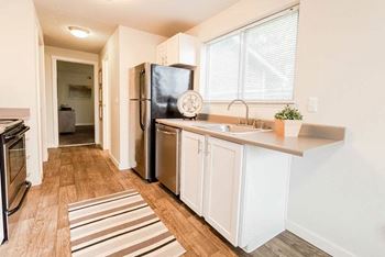 A kitchen with a black fridge, white cabinets, and a striped rug at Altitude Apartment, Tacoma, WA, 98444