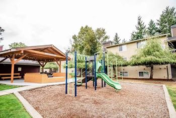 A playground with a green slide and a brown wooden structure at Altitude Apartment , Tacoma, 98444