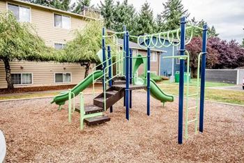 A playground with a green slide and a climbing frame at Altitude Apartment , Tacoma, WA