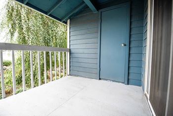 A blue door is on the right side of a porch at Altitude Apartment , Tacoma