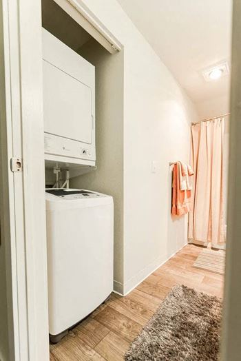 A white dryer is in a small room with a rug on the floor at Altitude Apartment , Tacoma, 98444