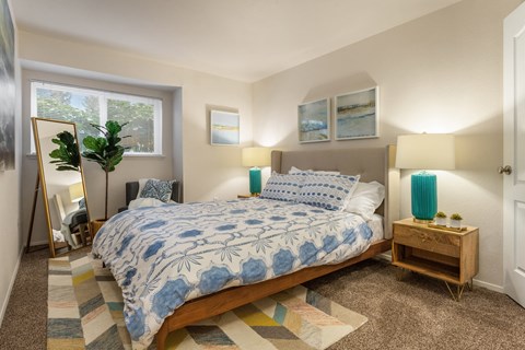 Bedroom with blue floral bedding and mid century nightstands at Bower Village Apartments, Kent
