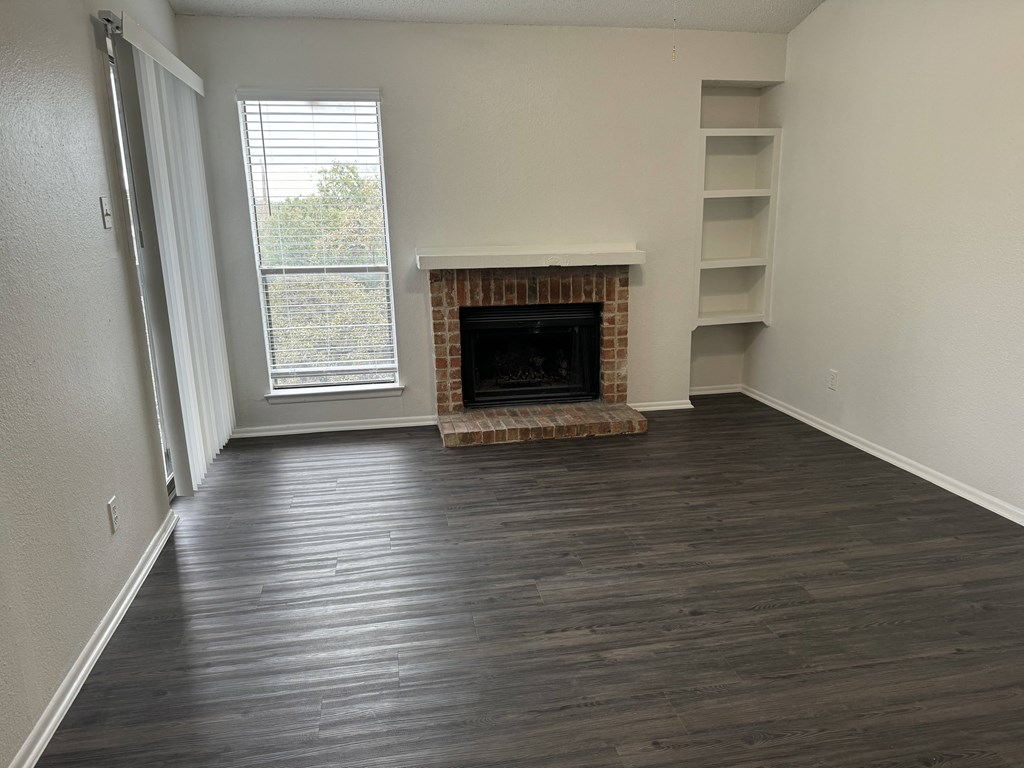 an empty living room with wood flooring and a fireplace  at Sunset Canyon, Texas