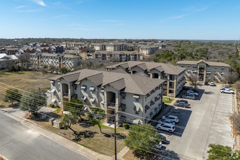 A large apartment complex with a parking lot in front at Logan Ridge Apartments, Apartments, San Marcos, TX
