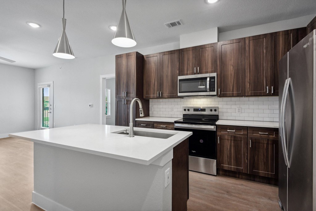 an empty kitchen with wooden cabinets and a white counter top at The Virginia, Seguin, Texas