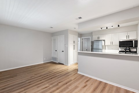 A kitchen with white cabinets and a wooden floor.