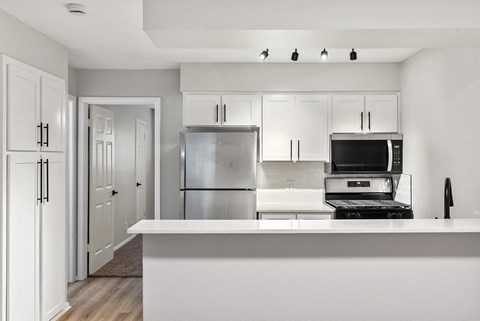 A modern kitchen with white cabinets and appliances.