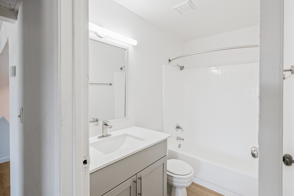 A white bathroom with a toilet, sink, and bathtub.