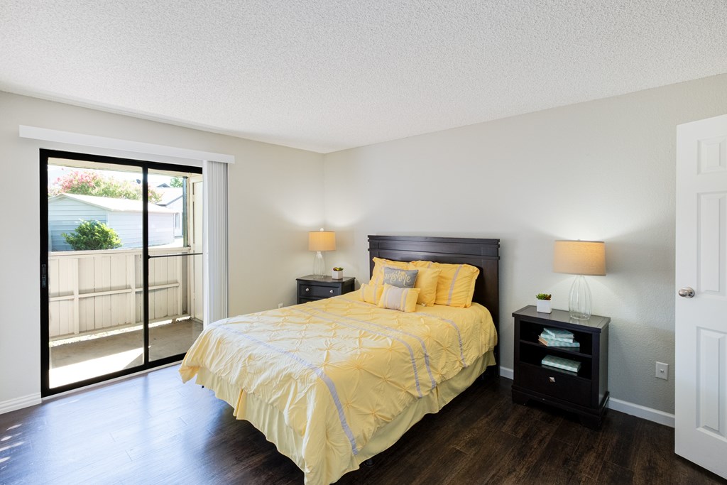 A bedroom with a bed, nightstand, and sliding glass doors.