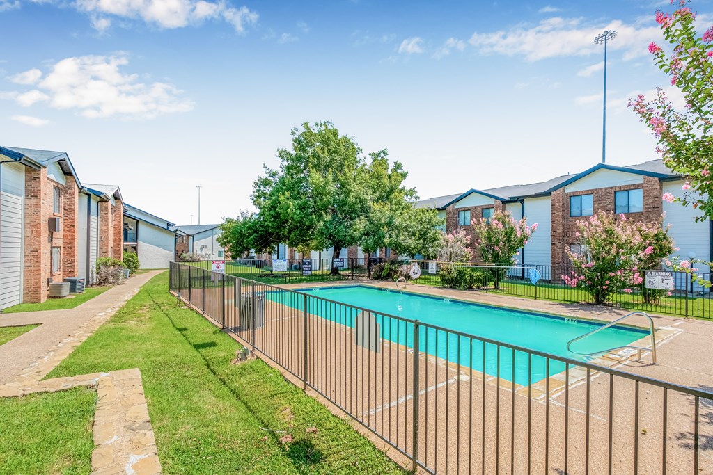 A pool surrounded by a fence in a sunny day.