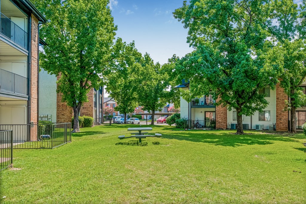 A park with a picnic table surrounded by trees and buildings.