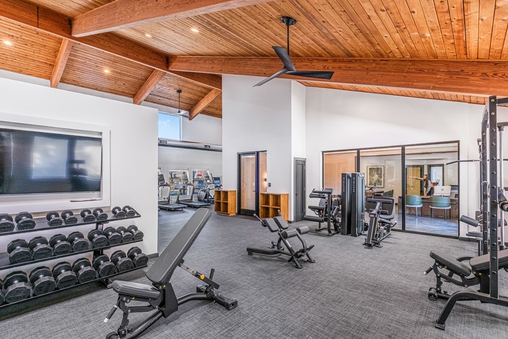 A spacious home gym with a variety of equipment including dumbbells, weight machines, and a bench press.