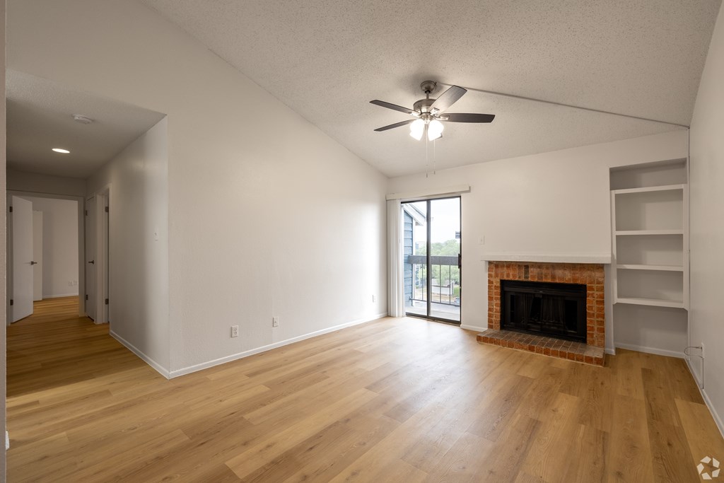 A room with a fireplace and a ceiling fan at Sunset Canyon Apartments, San Antonio