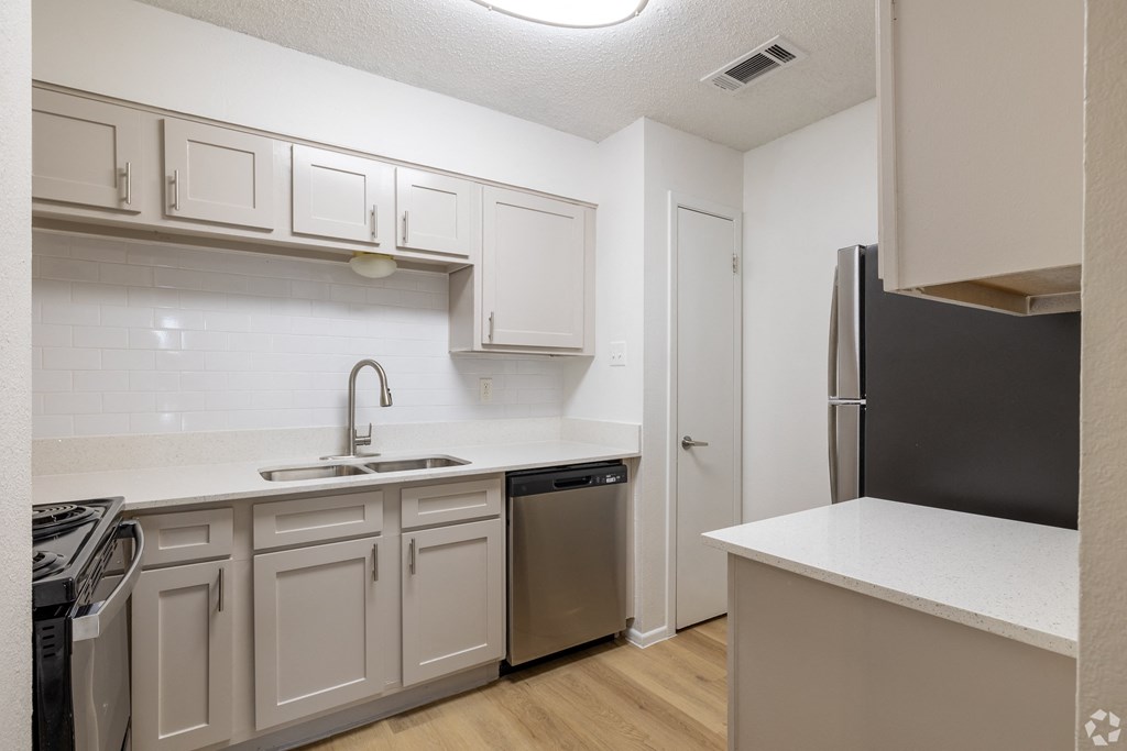 A kitchen with white cabinets and a black refrigerator. at Sunset Canyon Apartments, San Antonio, TX