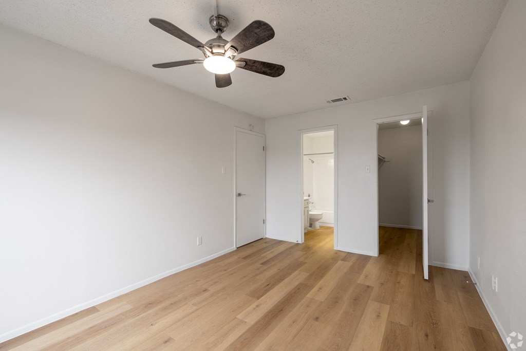 A room with a ceiling fan and wooden floors. at Sunset Canyon Apartments, Texas, 78232