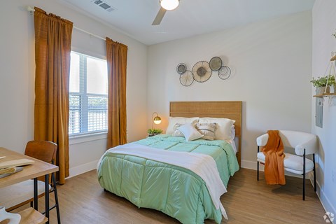 A bedroom with a bed, chair, and window at The Virginia Apartments , Seguin, TX