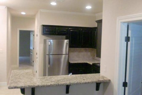A kitchen with a granite countertop and stainless steel appliances at Logan Ridge Apartments, San Marcos