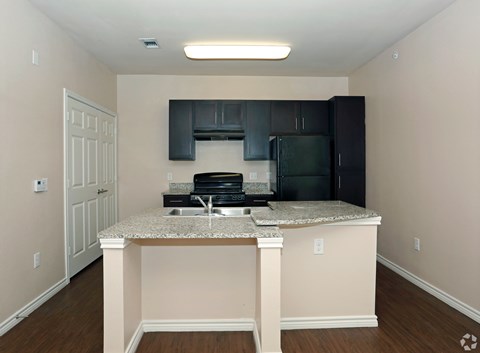 A kitchen with a granite countertop and black cabinets.