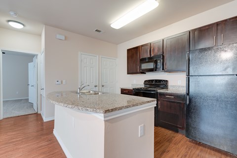 A kitchen with a granite countertop and a black refrigerator.