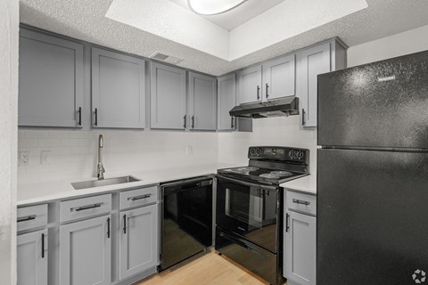 A kitchen with black appliances and grey cabinets.