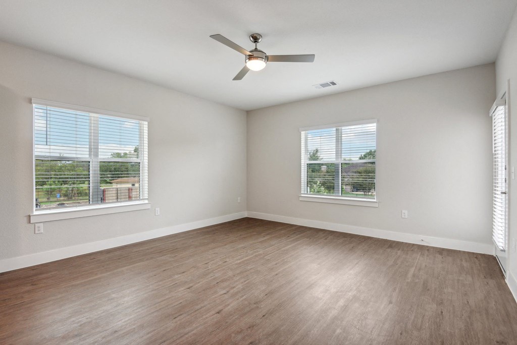 an empty living room with wood floors and a ceiling fan at The Virginia, Seguin
