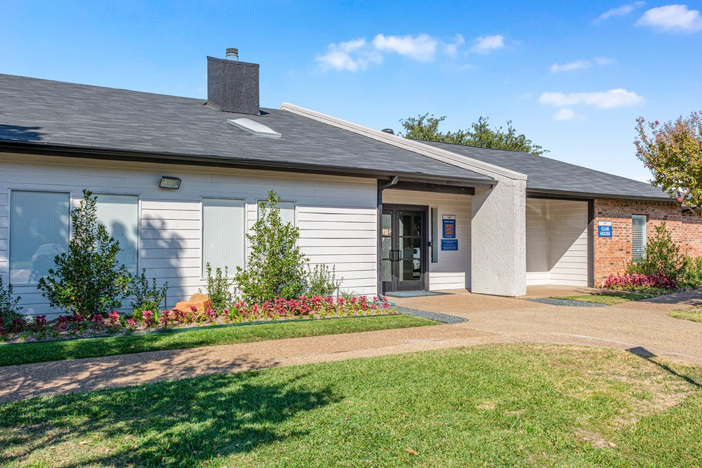 A small building with a grey roof and a white wall with a blue sign on it.