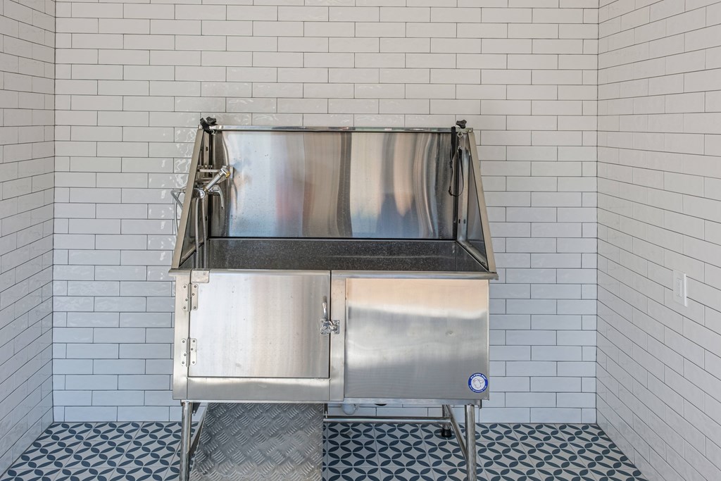 A stainless steel sink in a tiled bathroom.