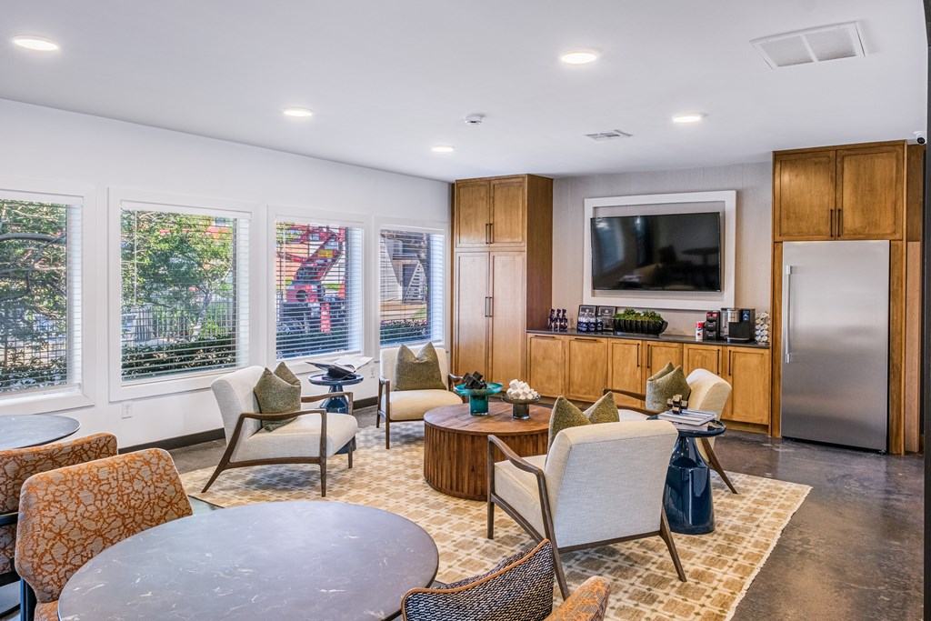 A modern living room with a television, a kitchen area, and a dining table.