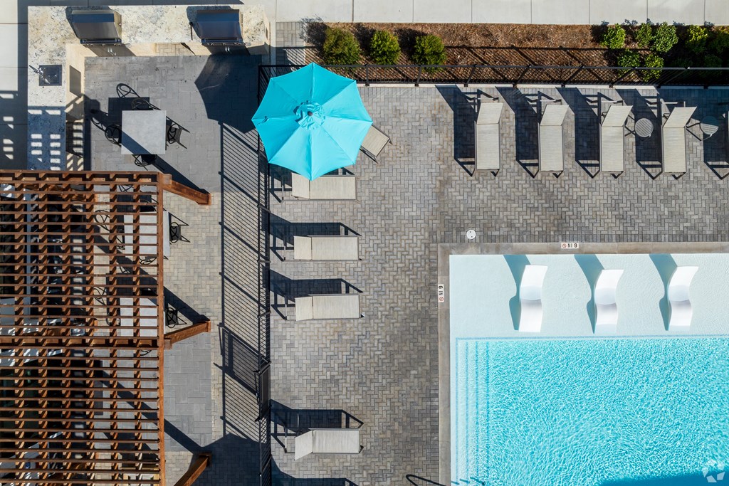A blue umbrella is on a patio next to a pool.
