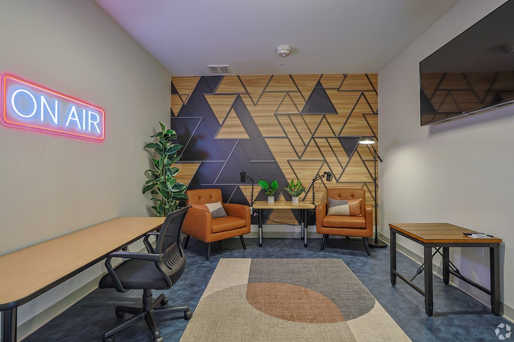 A room with a neon sign that says "ON AIR" and a wooden table with a plant on it.