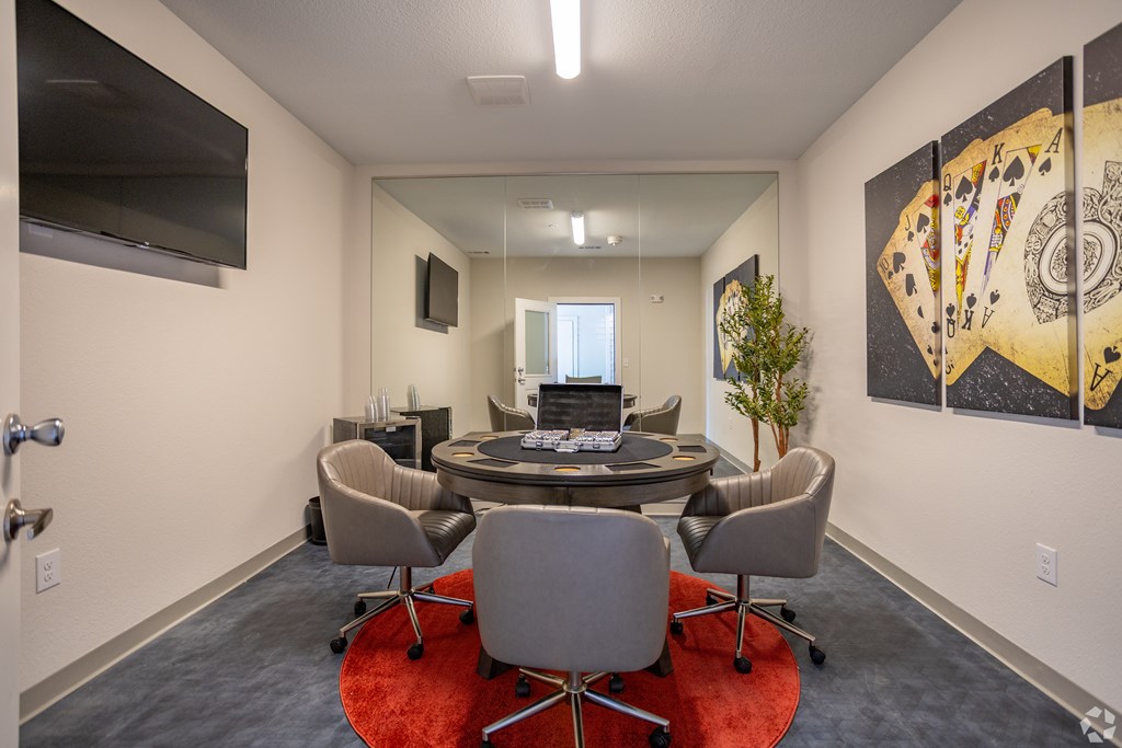 A conference room with a table surrounded by chairs and a television on the wall.