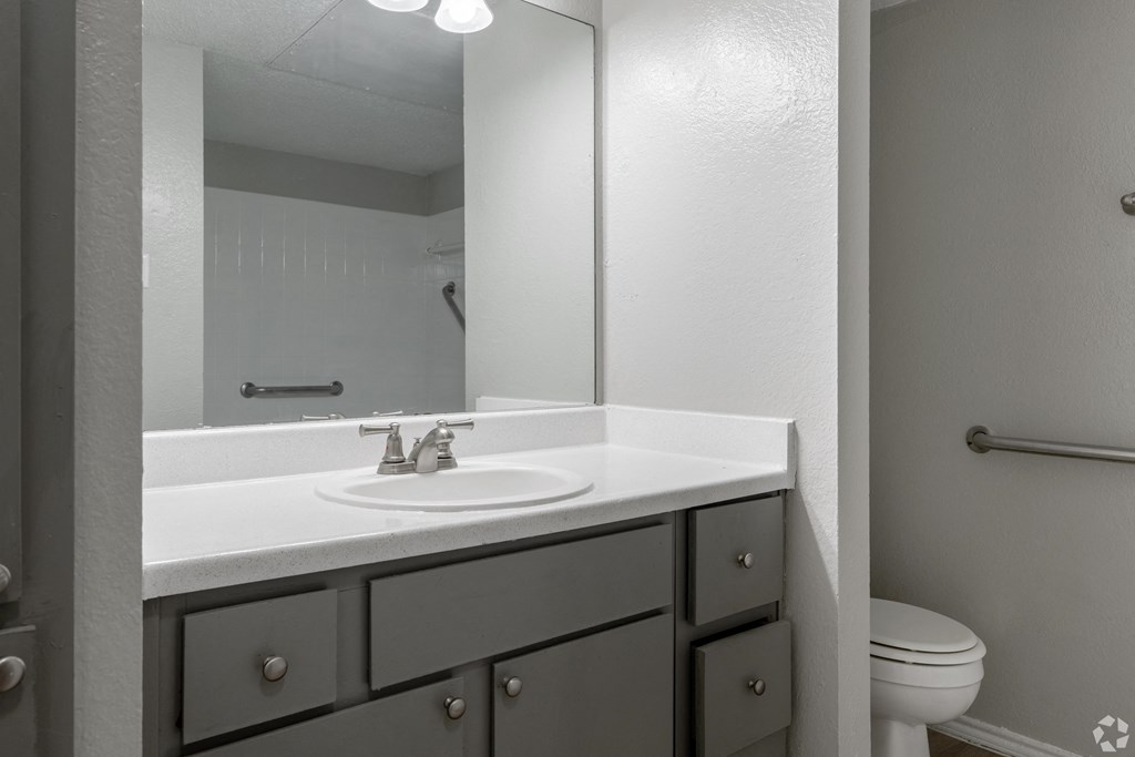 A bathroom with a white sink and grey drawers.