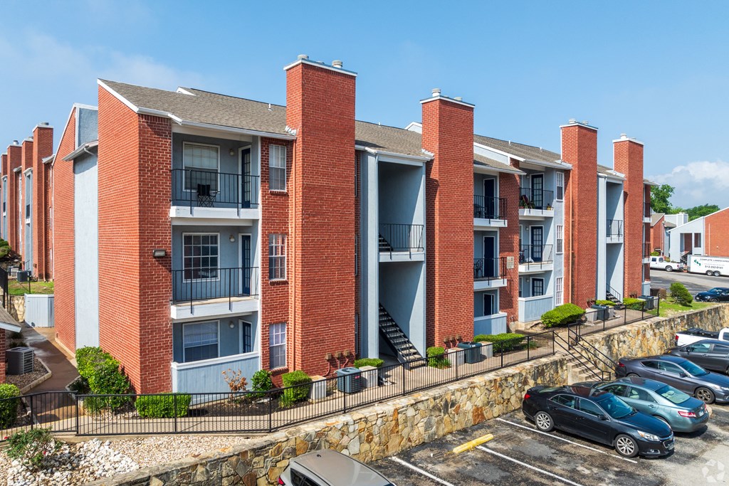 A red brick apartment building with a parking lot in front.